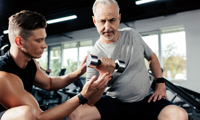 Personal Trainer helping an older adult with light weights