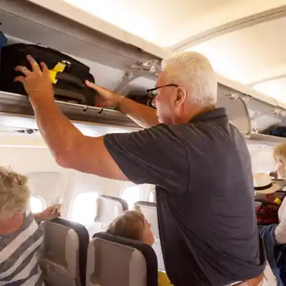Properly putting luggage in the overhead bin compartment of a plane