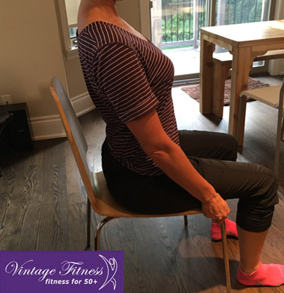 Woman sitting upright in a chair with good posture, showing a safe seated position to reduce back pain