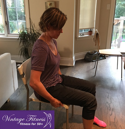 Woman sitting on a chair leaning forward with poor posture, demonstrating a common back pain trigger